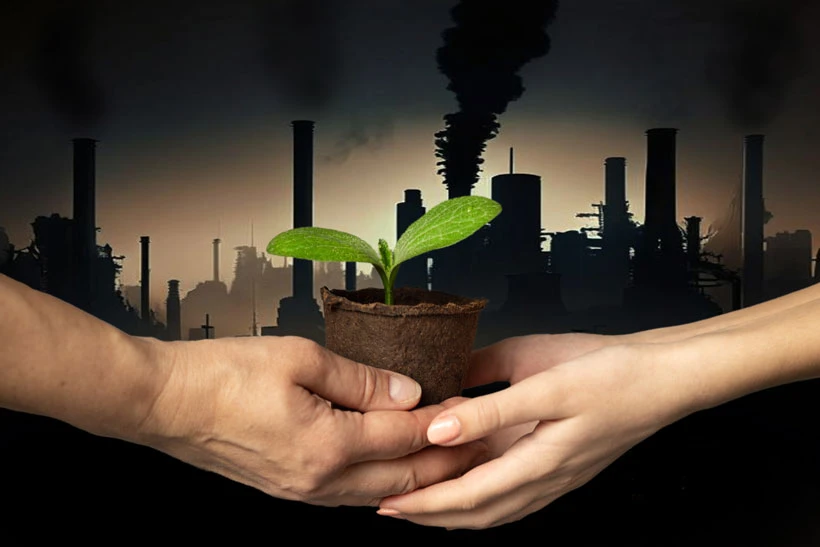Deux personnes se transmettent une jeune pousse verte devant une usine en activit&eacute;, illustrant la transition &eacute;cologique de l&rsquo;entreprise